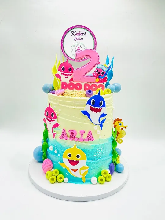 Pastel Baby Shark themed two-tier cake with ocean decorations