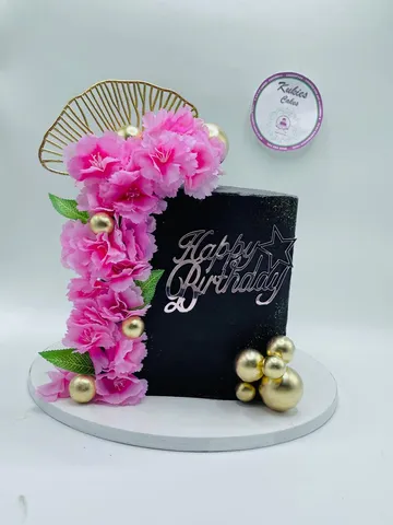 Black square cake with pink silk flowers and gold sphere decoration