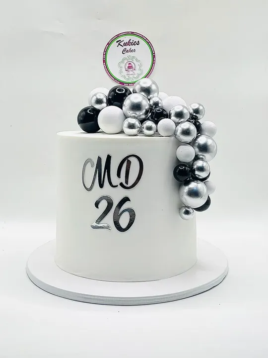 White cake with a cascading black, white and silver sphere garland and a mirror-silver birthday topper