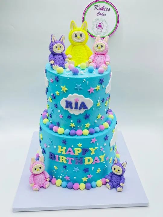 Two-tier blue cake with colourful fondant bunny monster figures and stars