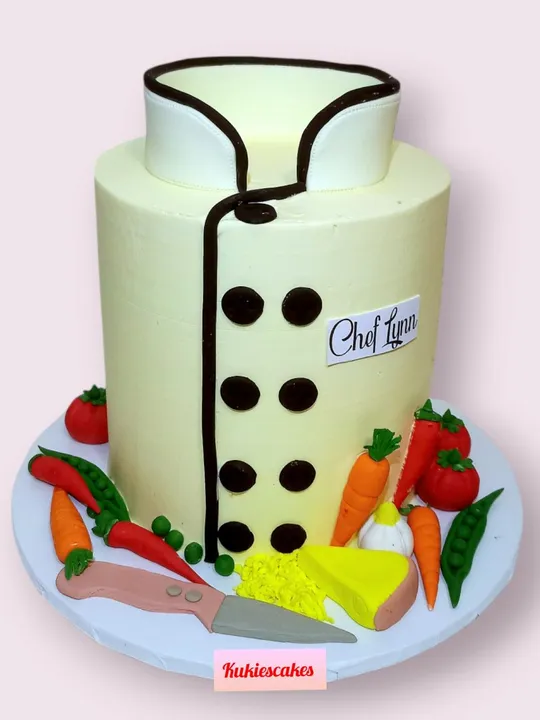Cake decorated as a chef's uniform with fondant vegetables and a knife