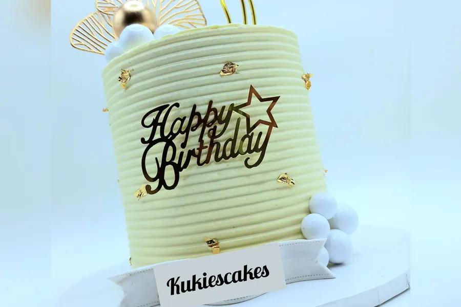 Cream ribbed cake with gold leaf flecks and a gold fan decoration