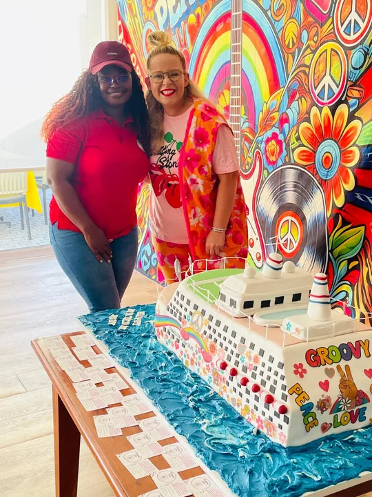 Two happy customers celebrating with the custom cruise ship cake made by Kukies Cakes