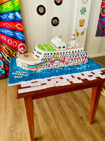 Cruise ship shaped novelty cake with a retro peace and hippie print