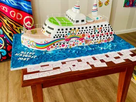 Cruise ship shaped novelty cake with a retro peace and hippie print