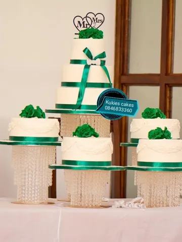 Green and white 3-tier wedding cake with matching minis on crystal stands