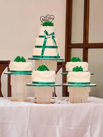 White 4-tier wedding cake with matching minis and an emerald ribbon