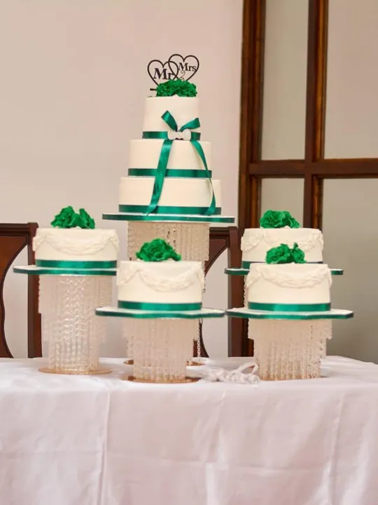 White 4-tier wedding cake with matching minis and an emerald ribbon