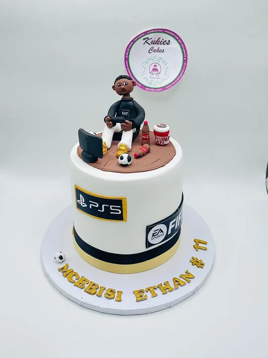White gaming themed cake with a fondant gamer figure and PS5 branding
