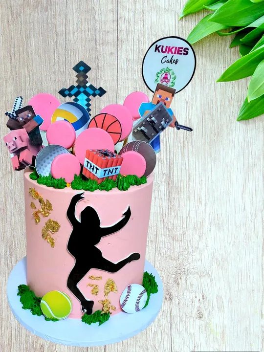 Pink cake with a dancer silhouette, gold leaf and sports ball decorations