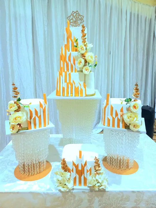 Tall gold flame textured wedding cake with matching minis and white flowers
