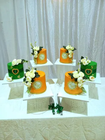 Green and orange round wedding cakes with gold monogram plaques