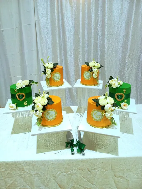 Green and orange round wedding cakes with gold monogram plaques