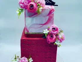 Two-tier pink and red marble effect wedding cake with a bride and groom topper