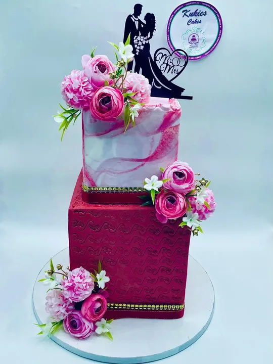 Two-tier pink and red marble effect wedding cake with a bride and groom topper