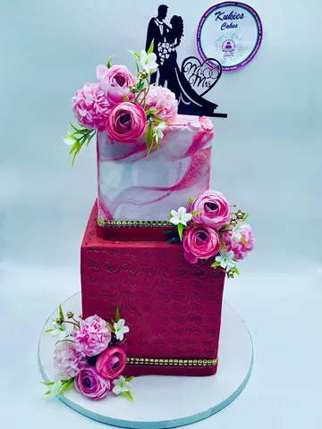 Two-tier pink and red marble effect wedding cake with a bride and groom topper