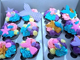 Cupcakes with fondant mermaid tails, starfish and shells over teal and purple buttercream