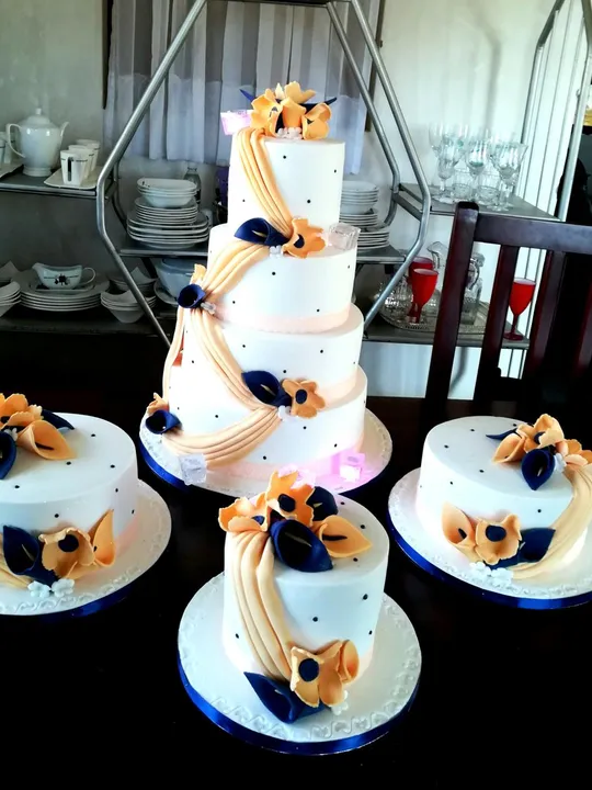 4-tier white wedding cake with matching minis in a peach and navy floral design