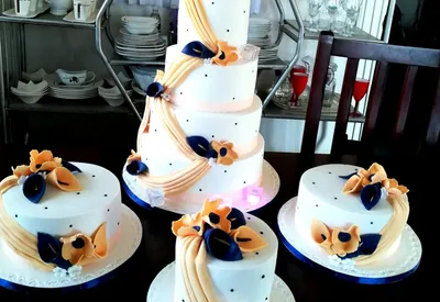 4-tier white wedding cake with matching minis in a peach and navy floral design