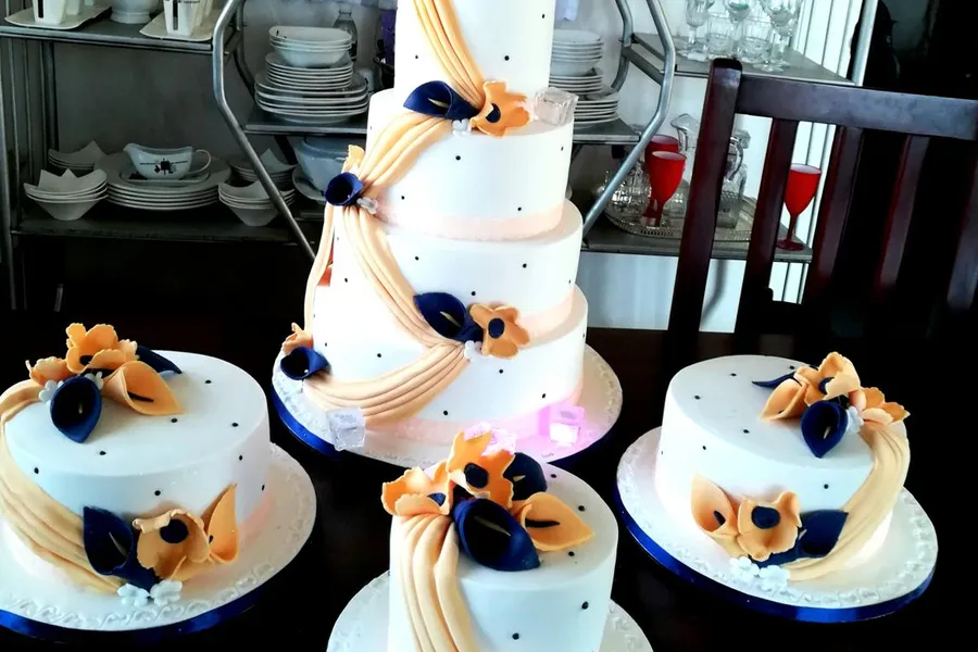4-tier white wedding cake with matching minis in a peach and navy floral design