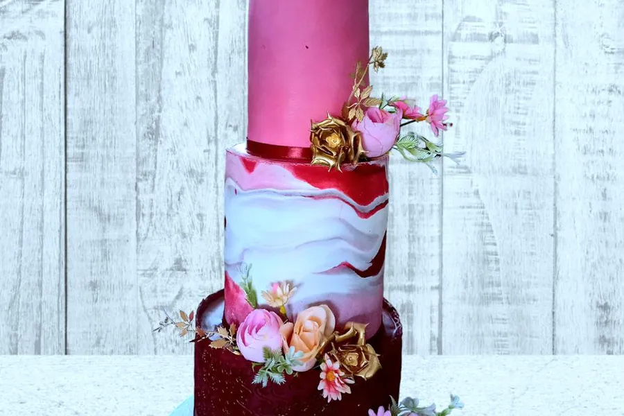 3-tier pink and red marble wedding cake with gold flowers