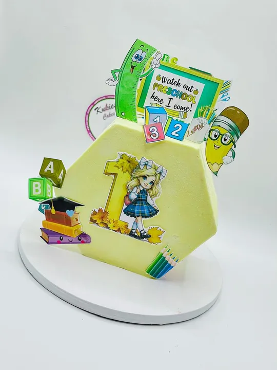 Pale yellow hexagonal cake with a preschool graduation topper