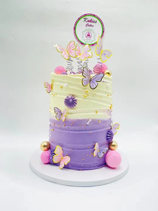 Tall purple ombre buttercream cake with iridescent butterflies and gold, pink and white spheres