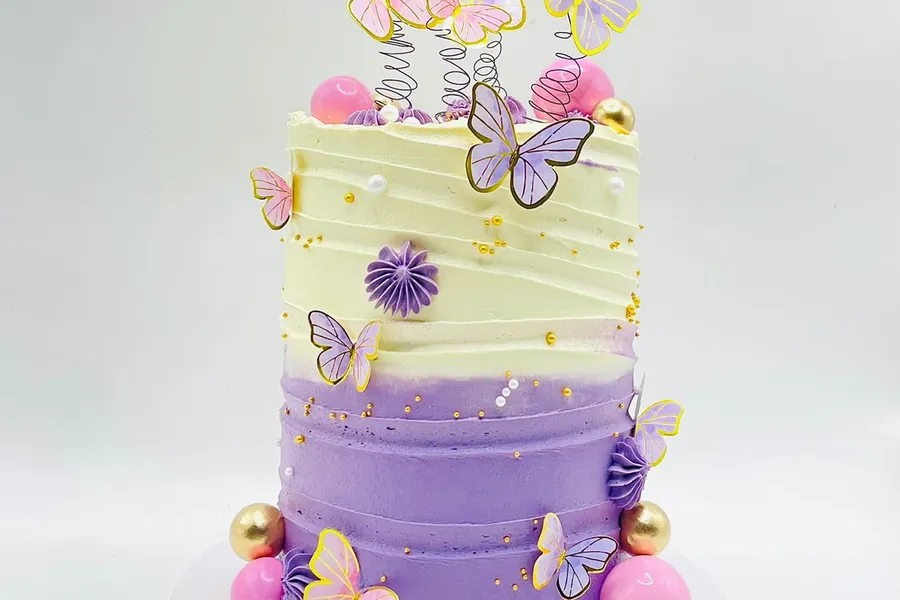 Tall purple ombre buttercream cake with iridescent butterflies and gold, pink and white spheres