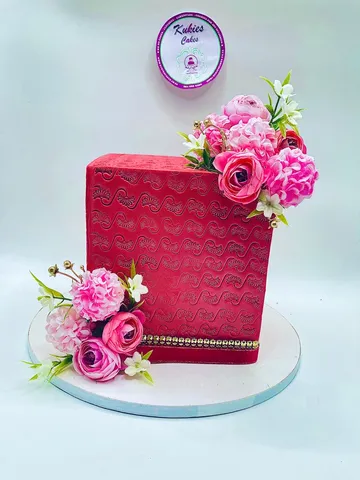 Red textured square cake with pink and white silk flowers and gold trim