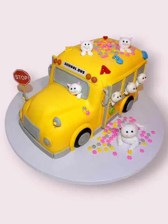 Yellow 3D school bus shaped cake with fondant kitten figures