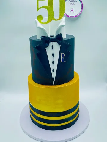 Navy tuxedo themed two-tier cake with a bow tie and gold 50 topper