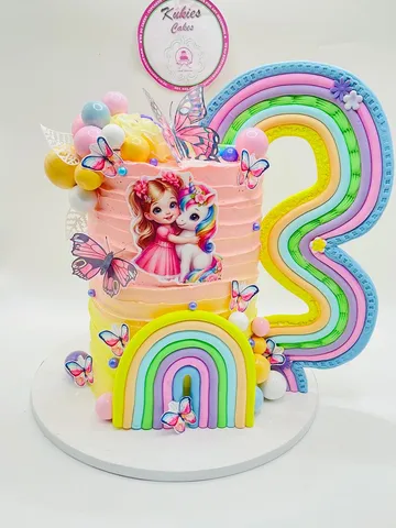 Pink to yellow unicorn themed cake with fondant rainbow arches