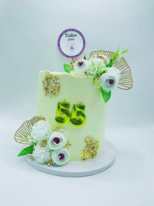 Pale green cake with white florals, gold leaf and a gold 55 topper