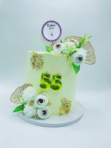 Pale green cake with white florals, gold leaf and a gold 55 topper