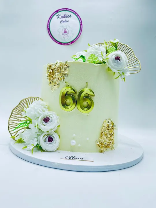 Cream cake with white florals, gold leaf and a gold 66 topper