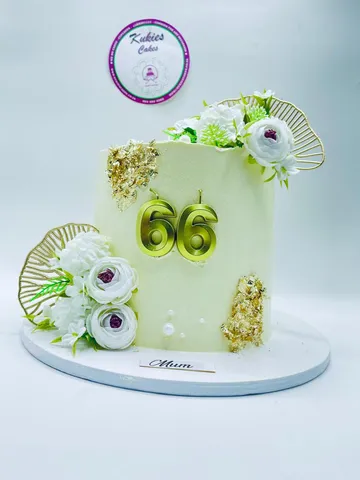 Cream cake with white florals, gold leaf and a gold 66 topper