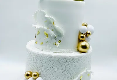 White two-tier marble effect cake with gold leaf and a gold 50 topper