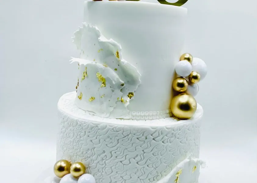White two-tier marble effect cake with gold leaf and a gold 50 topper