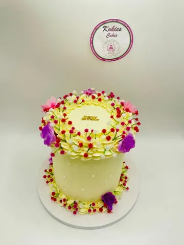 Pale yellow cake with a wreath of pink, red and purple wildflowers