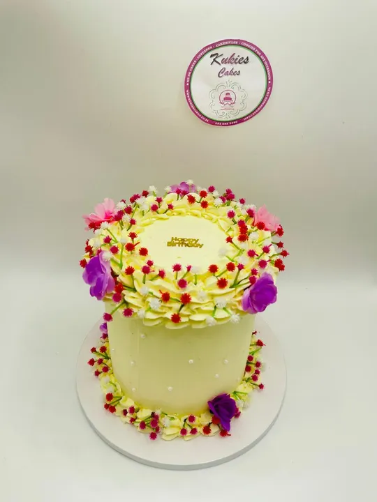 Pale yellow cake with a wreath of pink, red and purple wildflowers